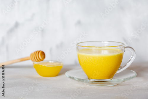 Golden milk in a glass mug on a gray background. Healthy drink from india.