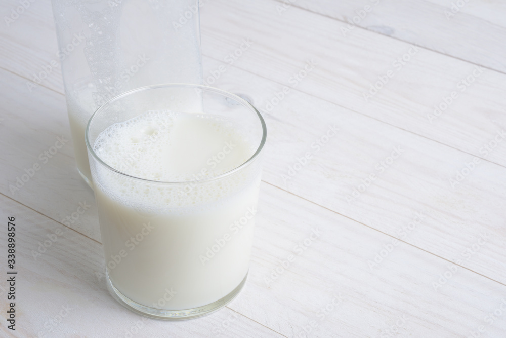 Vaso de leche y botella con tapón en la mesa blanca