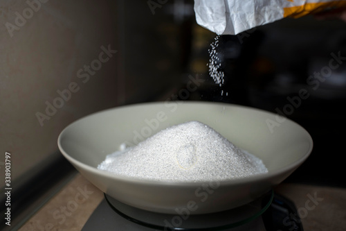 Pouring sugar into a deep plate. Close-up.