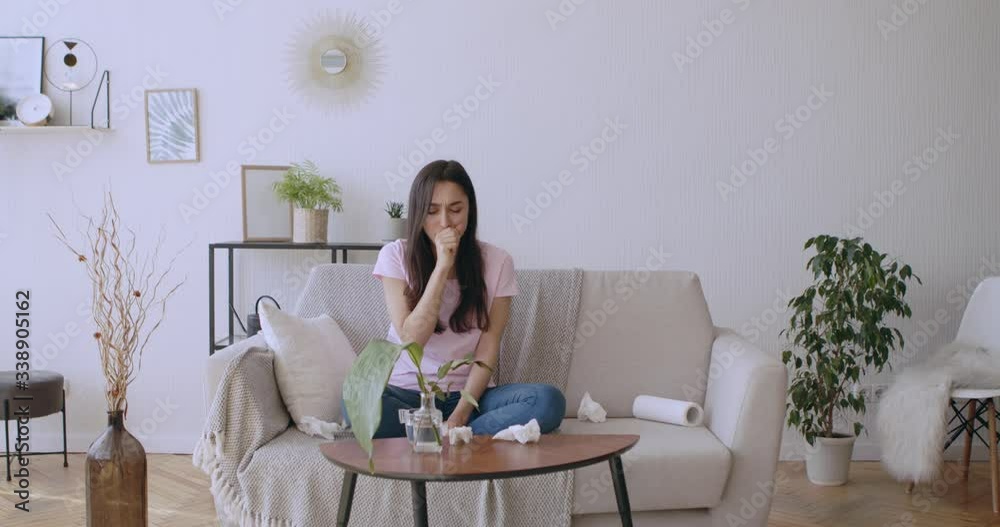 Young infected woman coughing and drinking water at home Young infected woman coughing and drinking water at home
