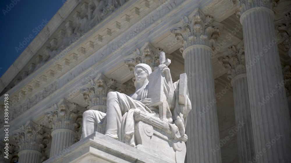 Slider to the left closeup of sculpture on the Supreme Court building of Justice with Equal Justice slightly out of focus in the distance. Slider to the left closeup of sculpture on the Supreme Court building of Justice with Equal Justice slightly out of focus in the distance.