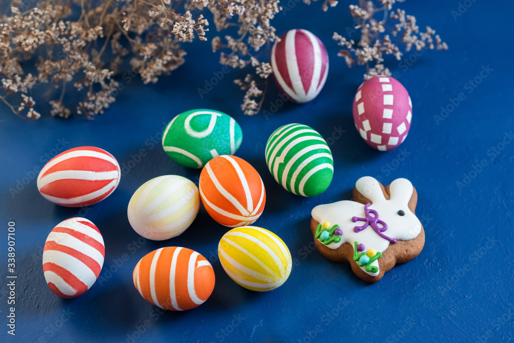 Attributes of the chrestian Easter holiday - colored eggs and gingerbread in the form of a rabbit on a dark blue background Attributes of the chrestian Easter holiday - colored eggs and gingerbread in the form of a rabbit on a dark blue background