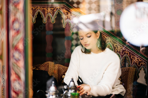 Portrait of pensive young woman drinking tea in a tea shop photo