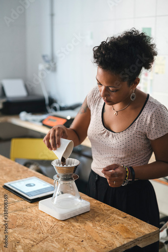 Woman working in a coffee roastery preparing fresh filtered coffee photo