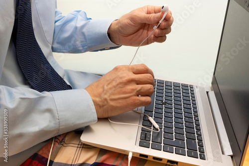 Man working with a laptop, using headphones and wearing a shirt, tie and pajama pants