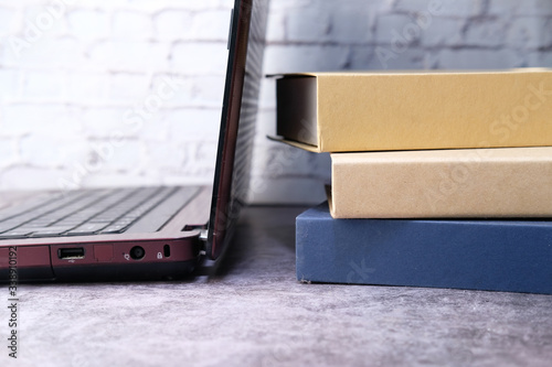 Stack of books with laptop on wooden table.