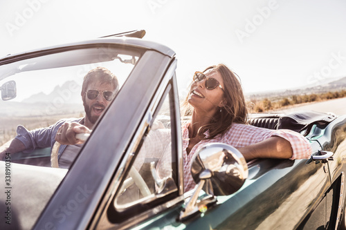 Happy couple in convertible car on a road trip photo