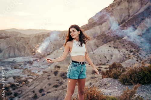 Portrait of smiling young woman with sparkler at sunset, Almeria, Spain