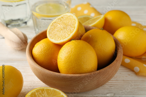 Bowl with fresh lemons on wooden background, close up