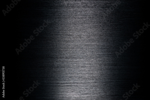 Texture of black anodized brushed aluminum with light reflection in the center
