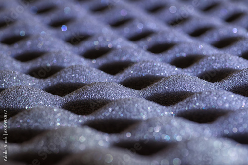 Abstract texture of grey soundproof acoustic foam with selective focus and shiny bokeh photo