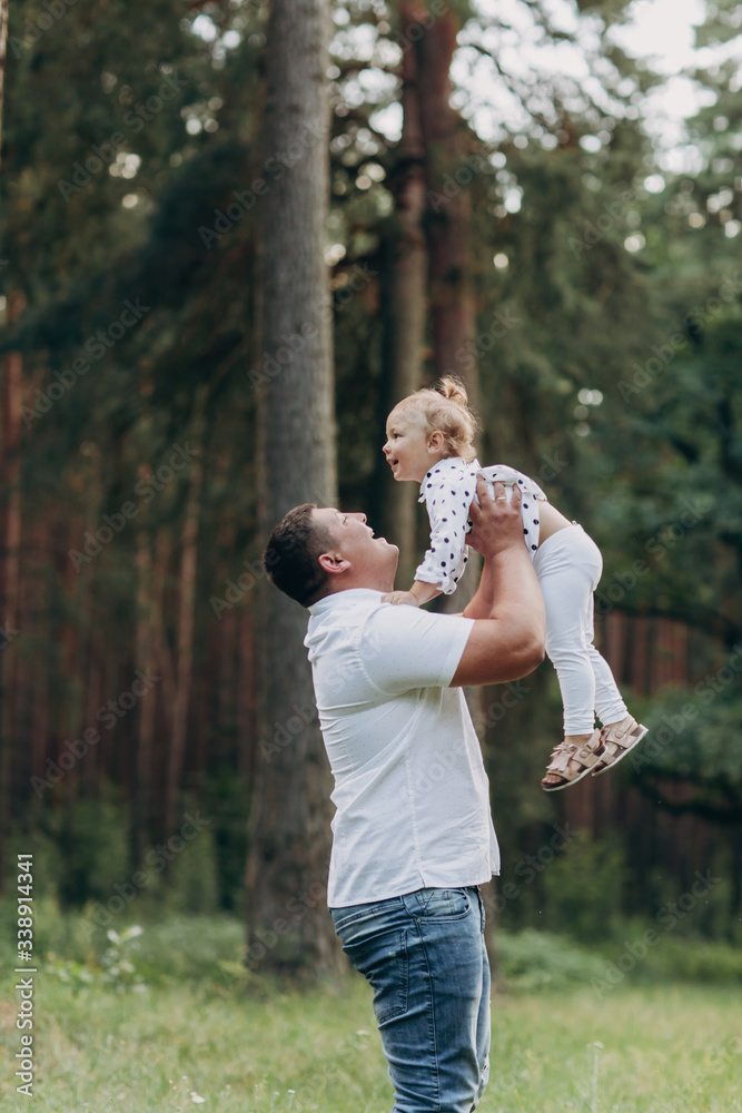 The father throws up and spins the daughter on nature on summer day vacation. Dad and girl playing in the park at the sunset time. Girl flying. Concept of friendly family. Closeup. selective focus The father throws up and spins the daughter on nature on summer day vacation. Dad and girl playing in the park at the sunset time. Girl flying. Concept of friendly family. Closeup. selective focus