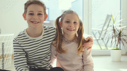 Happy teen brother and sister smiling and looking at camera in modern interior