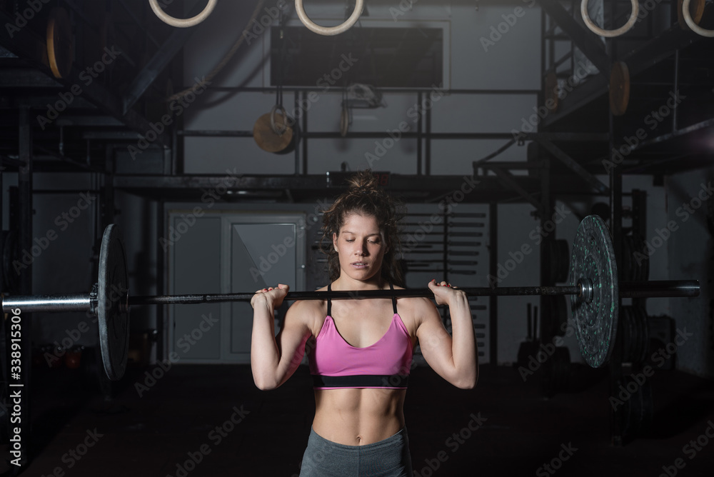 Young strong muscular fit girl with big muscles preparing for hard strength weightlifing or dead lift cross workout training with barbell weights in the gym real people Young strong muscular fit girl with big muscles preparing for hard strength weightlifing or dead lift cross workout training with barbell weights in the gym real people
