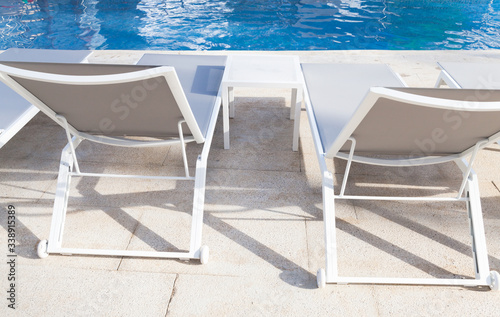 Vacant white sunloungers by a pool