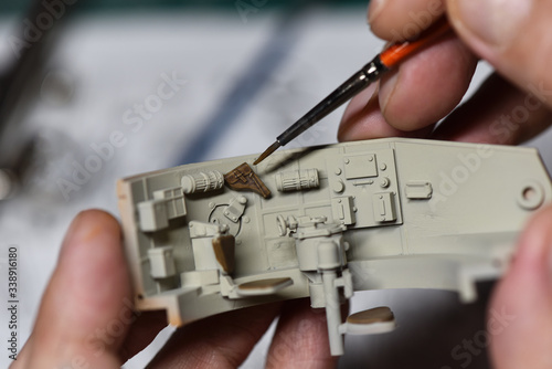 Plastic Modeling and model building. Close up of male hands painting and assembling scale model of a tank. Hobby and leisure at home. Hobbies in quarantine. Modelism macro shot.  © NikonLamp