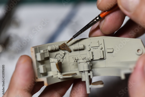 Plastic Modeling and model building. Close up of male hands painting and assembling scale model of a tank. Hobby and leisure at home. Hobbies in quarantine. Modelism macro shot.  photo