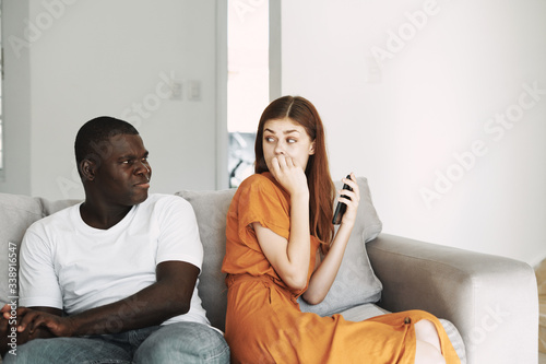 Man and woman at home on the couch with a phone in their hands chatting © SHOTPRIME STUDIO