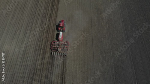 Top view of a spacious meadow getting scattered with seeds by a combine . Agriculture, tractor plow the earth in field, view from height.