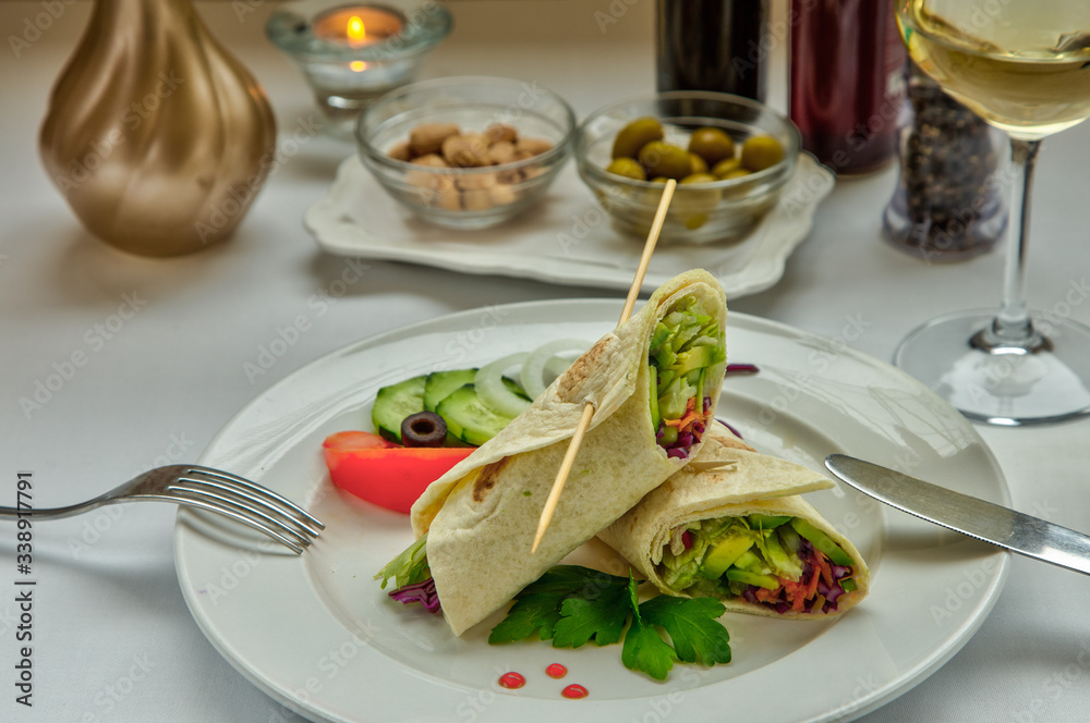Vegetable rolls. Pancakes with vegetables. Pita bread wrapped in cabbage, cucumber, avocado, carrots, cabbage, salad. The dish is decorated with onion rings, cucumber slices, sweet red pepper and mint