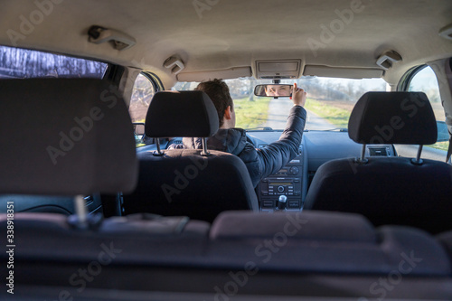 young driver adjusts the rearview mirror in a car