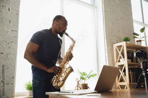 Wallpaper Mural African-american musician playing saxophone during online concert at home isolated and quarantined
