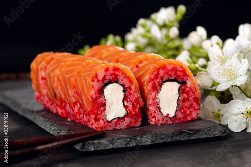 tasty sushi rolls on a gray background with traditional chopsticks and fish