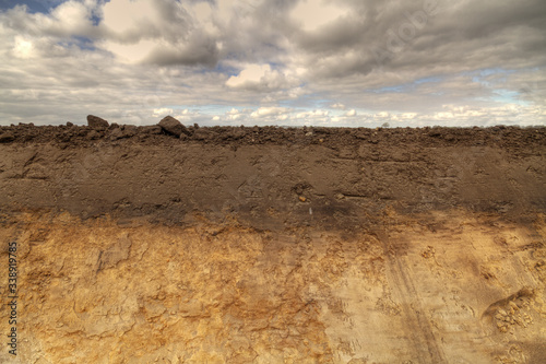 The side of a freshly dug field drainage ditch showing soil stratification humic topsoil and iron precipitation in subsoil