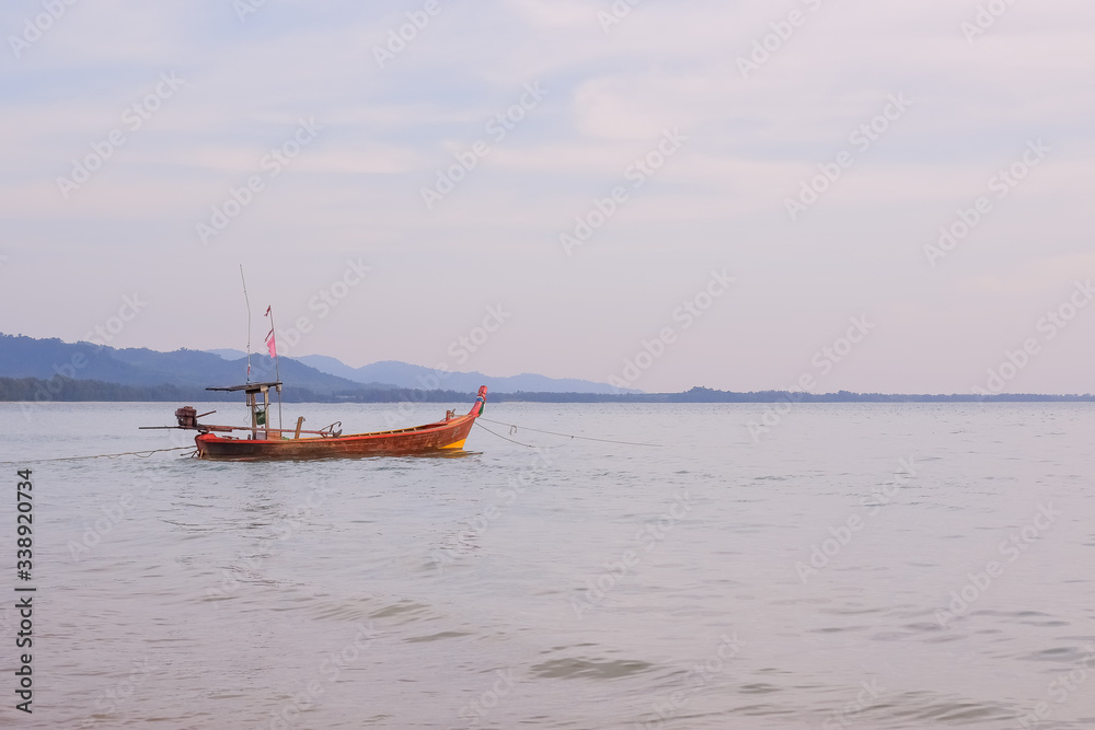 longtail boat standing near the shore at sunset.Beautiful sunset of fishing village in Phang Nga Bay with longtail wooden fishing boat ,Thailand.Travel by Asia. Landscape with traditional fishing boat