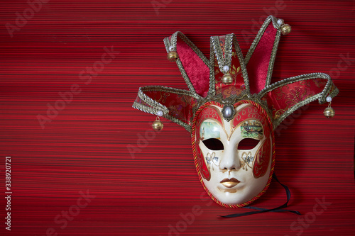 Traditional carnival venetian mask with rich decor on a red background, selective focus