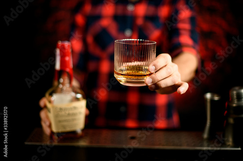 Close-up Barman's hand holds glass with alcoholic drinks.