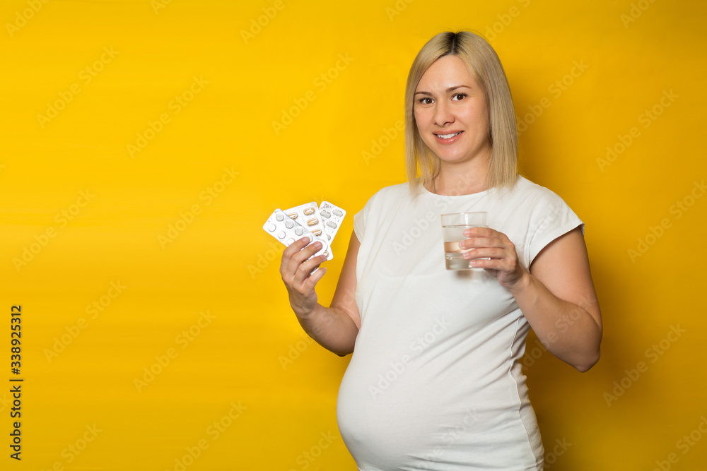 happy pregnant woman, blonde holds in his hands the tablets and a glass of water. safe medications for pregnancy happy pregnant woman, blonde holds in his hands the tablets and a glass of water. safe medications for pregnancy
