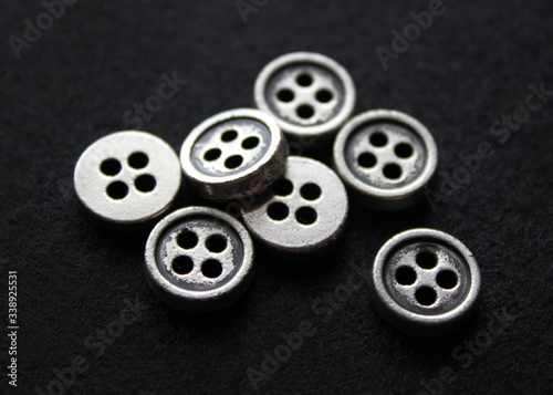 Small metal buttons. Vintage buttons. Accessories for clothes. Close-up. Black background.