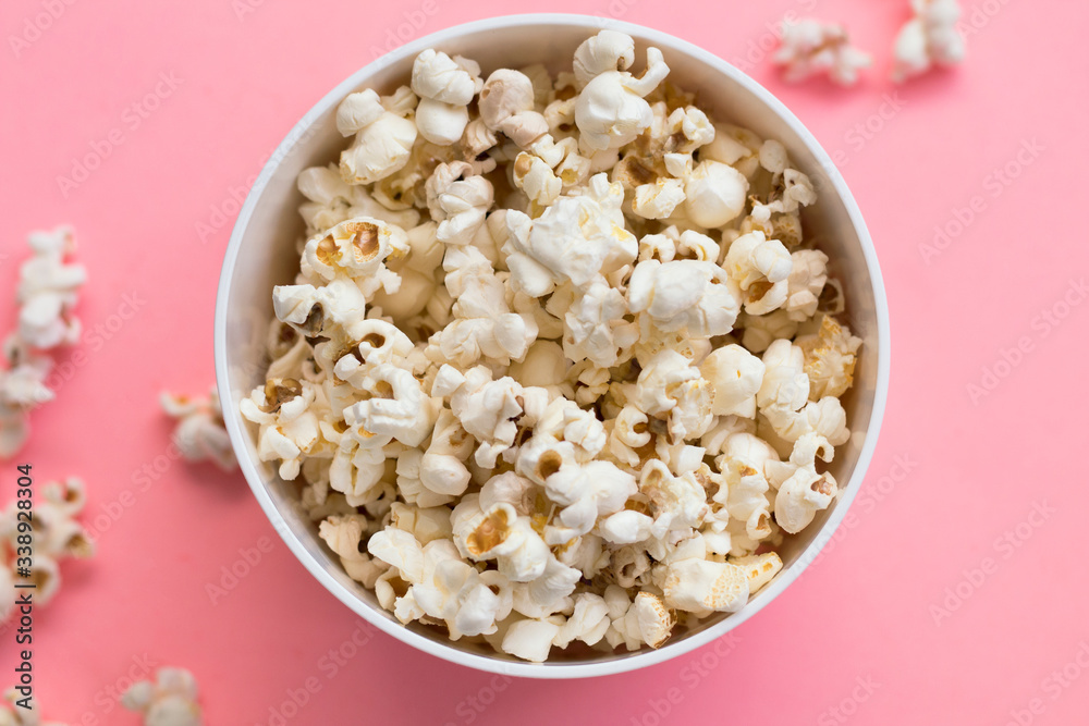 Popcorn in a bowl on pink background, top view Popcorn in a bowl on pink background, top view
