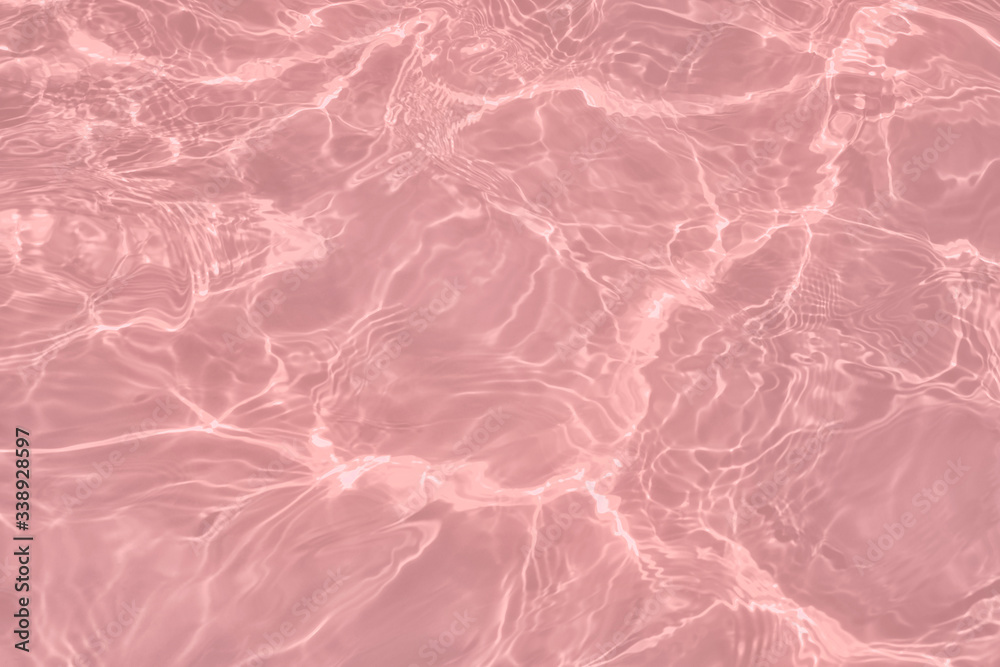 Fototapeta premium Closeup of calm clear water surface with water splashes in trendy pink color. Swimming pool water texture. Trendy fresh abstract nature background. 2020 color trend concept.