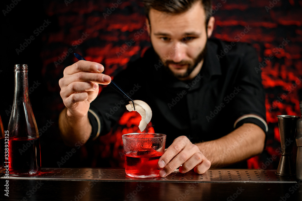 professional bartender decorates cocktail glass with two pieces of coconut