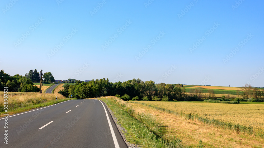 empty country road in the countryside against blue sky with copy space in Bavaria, Germany
