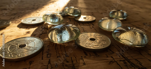 Closeup of a pile of Norwegian money on a cork background, illuminated by a beam of sunlight.