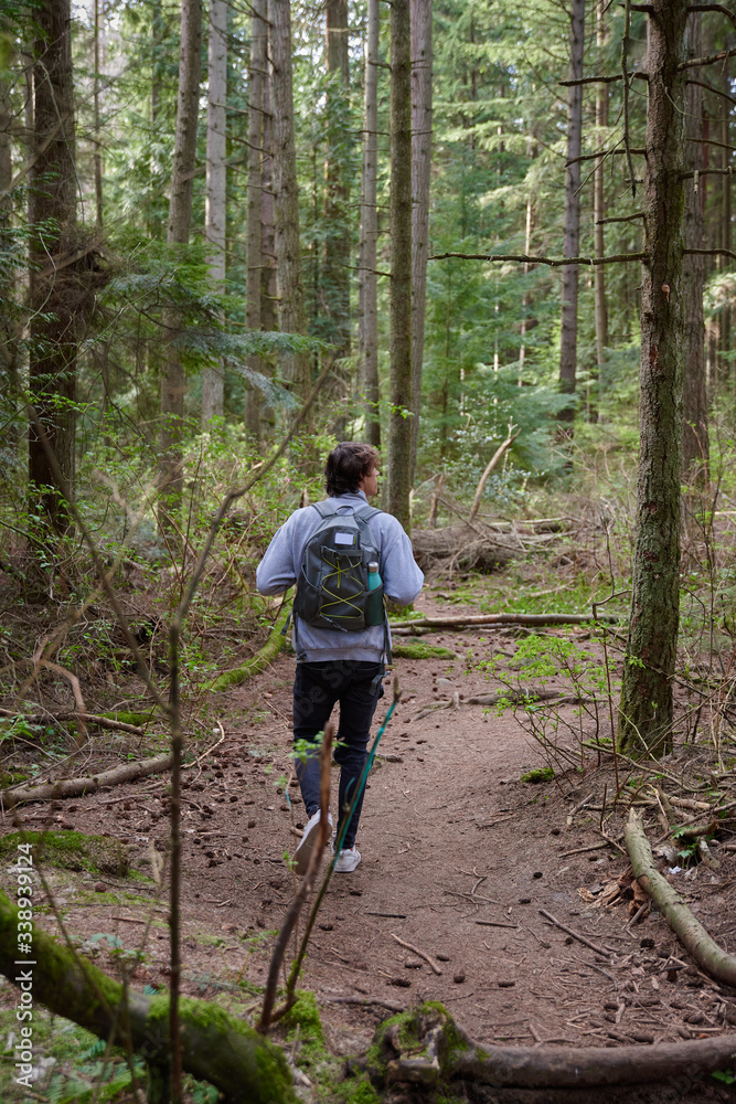 Obraz premium Teenager walking on the forest with a backpack and a water bottle