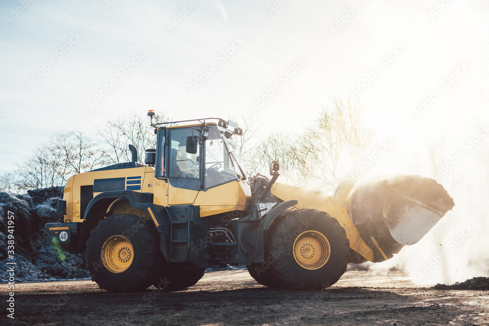 Wheel loader working on heap with biomass for composting Wheel loader working on heap with biomass for composting