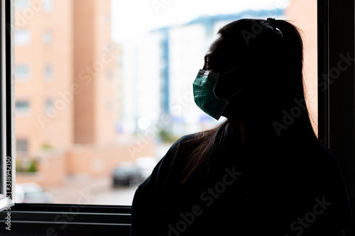 Close-up of the profile of a young and serious woman wearing a medical protective mask