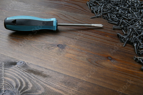 crosshead screwdriver with wood screws on brown wooden background with copy space