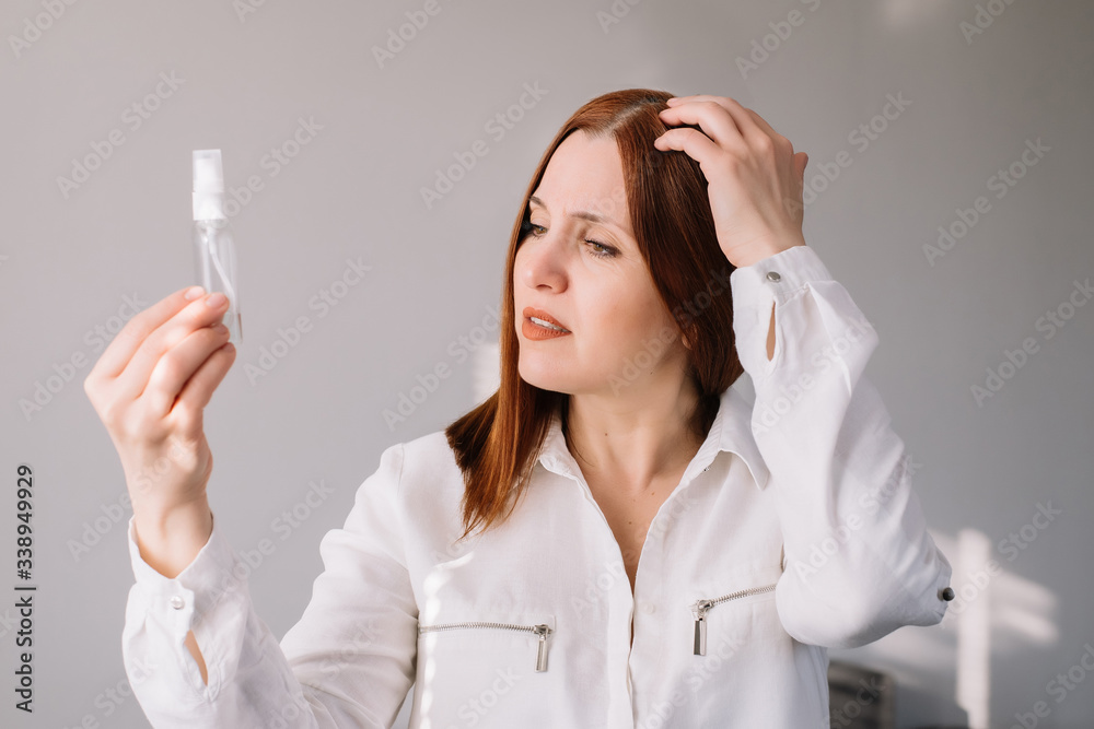 Adult woman looking and check at the sanitizes gel at home. Woman uses an antibacterial hand cleaner. Adult woman looking and check at the sanitizes gel at home. Woman uses an antibacterial hand cleaner.