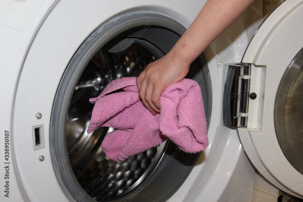 Woman hands loading towel into wahing machine. Woman hands loading towel into wahing machine.