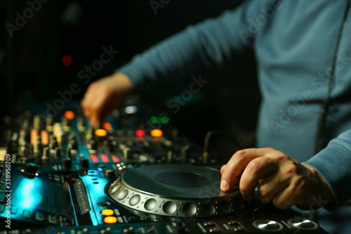 dj is mixing tracks at party in night club. disc jockey playing music on the modern turntable close up