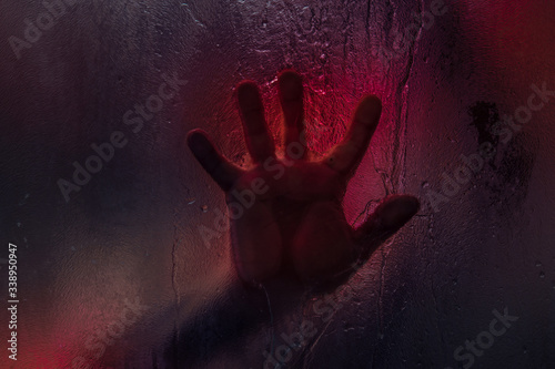 Fotografie Bloody hand against wet shower glass