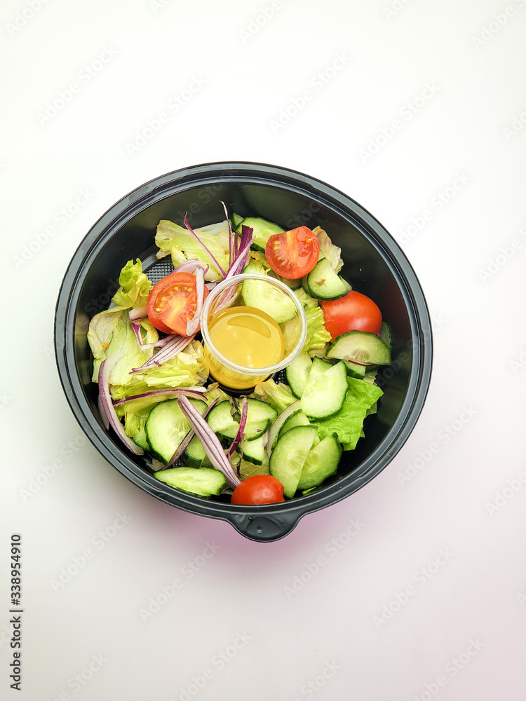 Plastic plate with vegetable salad on an isolated white background. The concept of food delivery.