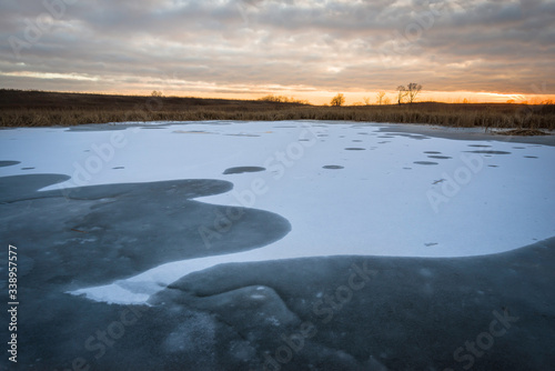 Sunset sky over the shoreline of a frozen wetland habitat. © Mark Baldwin