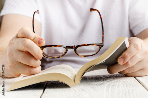 Reading book close up view in hands with glasses