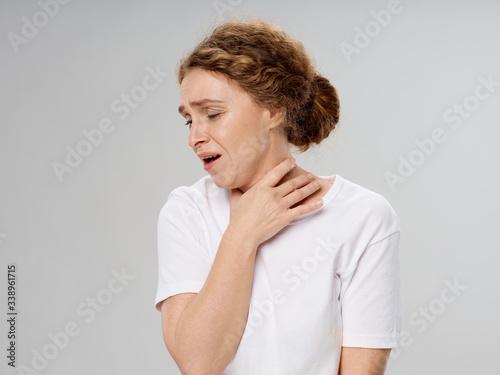 A woman in a white T-shirt holds on to the throat of a health problem